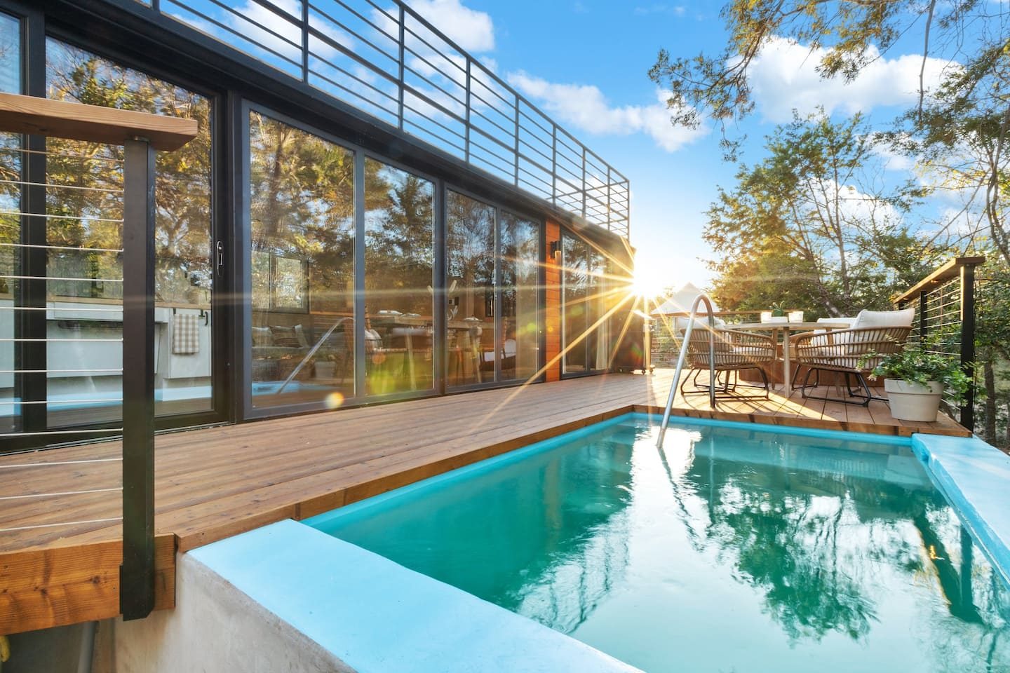 A glass-walled pavilion and pool deck at sunset